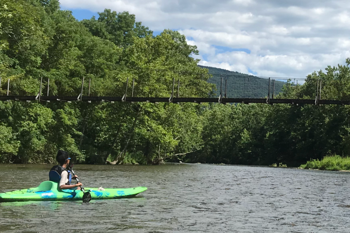 A kayaker paddling under a bridge