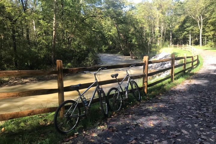 Two bikes resting on a fence along the Jackson River