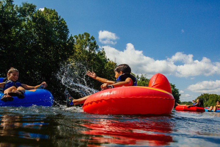 Kids in tubes splashing each other as they float down the river